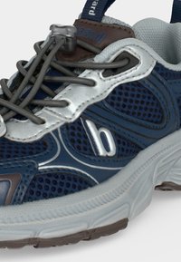 Chaussure de sport bleue et grise en tissu mesh, accents réfléchissants, lacets élastiques avec dispositif de verrouillage, et semelle blanche texturée.