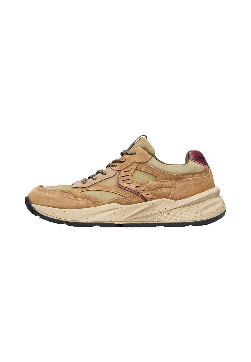 Zapatilla de ante beige con acentos en verde oliva, que presenta una suela media gruesa con manchas, cordones redondos y un detalle en el talón en color marrón oscuro.