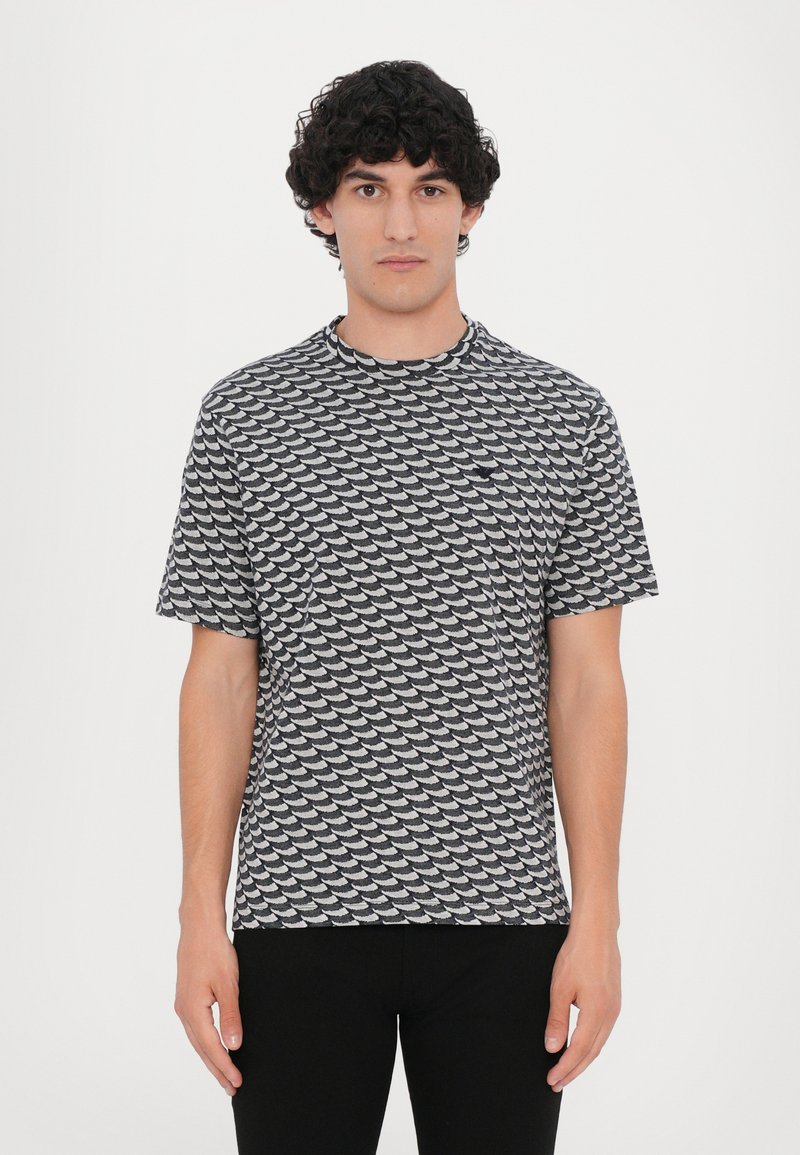 Grey short-sleeve t-shirt featuring a repeating wave pattern in black and white, cotton material, crew neckline, and relaxed fit.