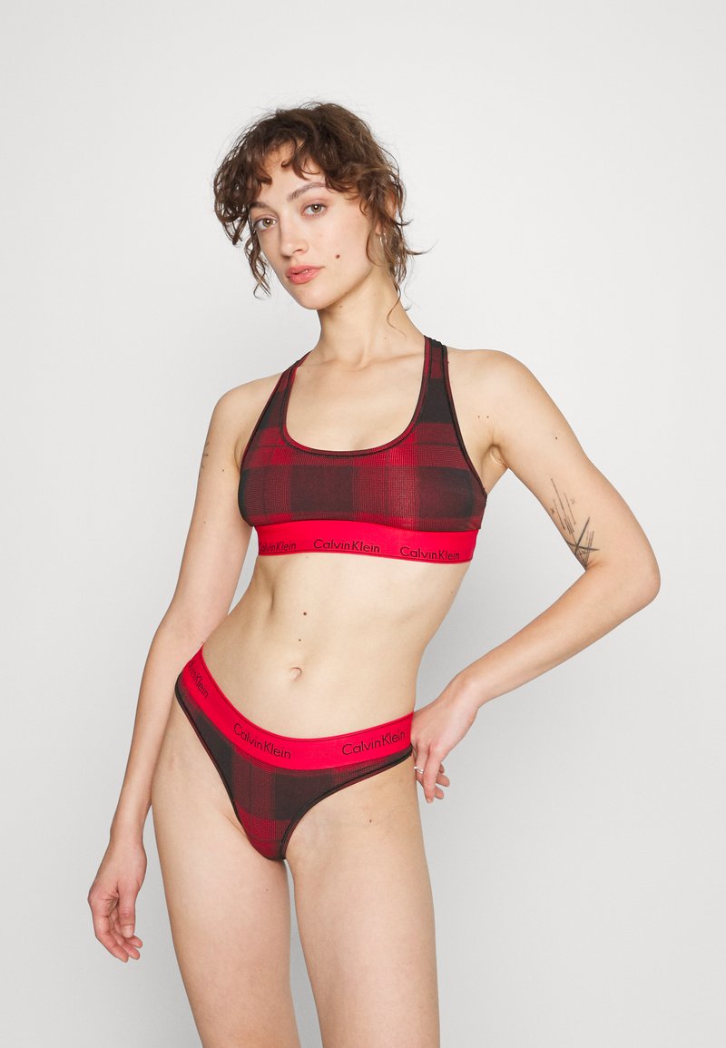 Červený a čierny kockovaný bralette a tanga set s výrazným logom "Calvin Klein" na elastických pásikoch; mäkká, elastická látka s priliehavým strihom.