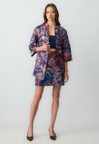 Multicolor Satinjacke und Rock-Set mit welligem, abstraktem Muster in Blau-, Pink- und Lilatönen. Kurze Ärmel und taillierte Passform.