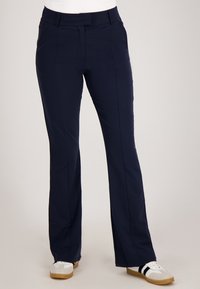 Navyblauwe op maat gemaakte broek met een recht model, met een gladde textuur, zijzakken en een discreet elastiek; gedragen met witte sneakers.