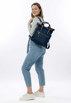 Navy blue nylon backpack with leather accents, two top handles, and adjustable shoulder straps. Features a front zipper pocket and a textured finish.