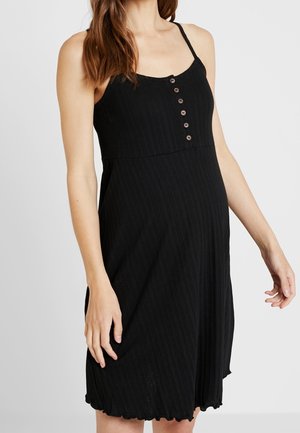 Robe noire côtelée avec bretelles fines et détail de boutons sur le devant. Ourlet évasé avec des bords légèrement festonnés. Texture douce.