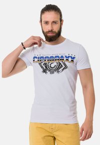 Weißes Baumwoll-T-Shirt mit einem grafischen Druck "CIPOBAXX" in Blau und Gold über einem maschinenähnlichen Design, kurze Ärmel.