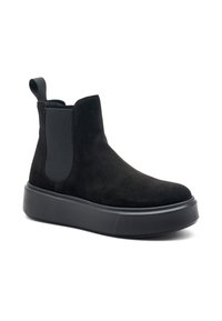 Stivaletto in camoscio nero con pannelli laterali elastici, con linguetta sul retro e suola piatta in gomma nera spessa. Texture liscia con una leggera lucentezza.