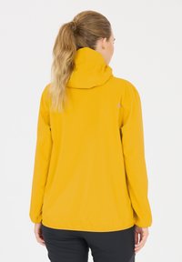Gul vandtæt jakke med hætte, letvægtsstof, elastiske cuffs og en afslappet pasform. Velegnet til udendørs aktiviteter.
