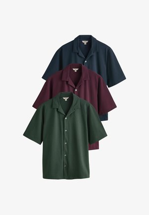 Trys trumpomis rankovėmis marškiniai su sagomis tamsiai žali, vyno raudonos ir tamsiai mėlynos spalvos, kiekvieni su stovyklos apykakle ir sagomis priekyje.