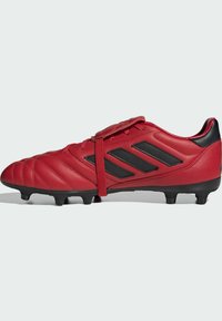Scarpa da calcio in pelle rossa con accenti neri, tre strisce nere, parte superiore testurizzata e suola in gomma nera con tacchetti visibili per la trazione.