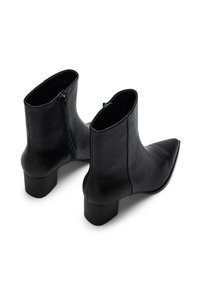 Botines de cuero negro con punta puntiaguda, tacón bloque de altura media y cremalleras laterales. Textura lisa con un diseño elegante.