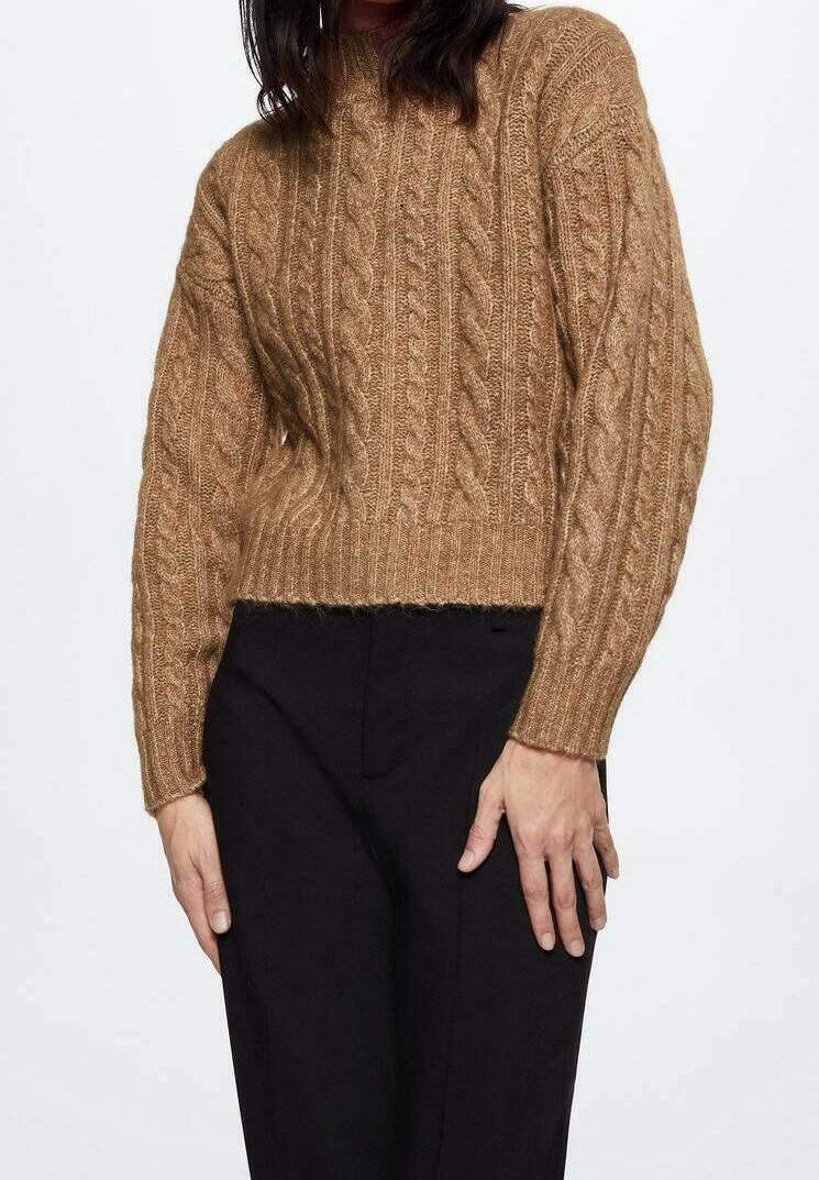 Pull en tricot torsadé marron avec un design court, des manches longues et une finition texturée, associé à un pantalon noir.