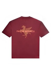 Maroonsin lyhythihainen T-paita, jossa on oranssipinnoitettu Pegasos-grafiikka ja "PAS DE MONACO" -teksti keskittyneenä selässä.