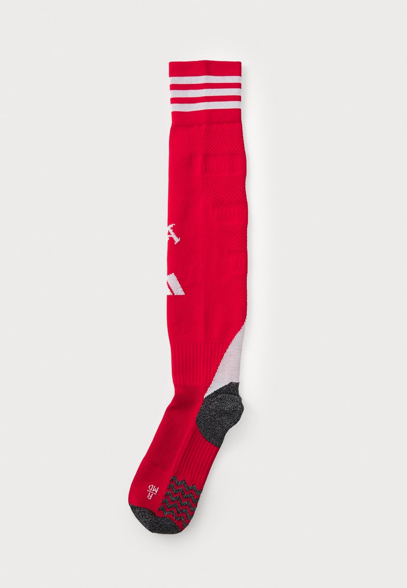 Chaussette rouge à hauteur de genou avec des rayures blanches sur le dessus. Présente des motifs texturés et des sections de talon et de orteil rembourrées en gris.