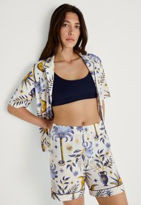 Kortärmad skjorta och shorts set med ett dekorativt mönster i blått, gult och vitt. Tillverkat av lättviktig tyg. Elastisk midja.