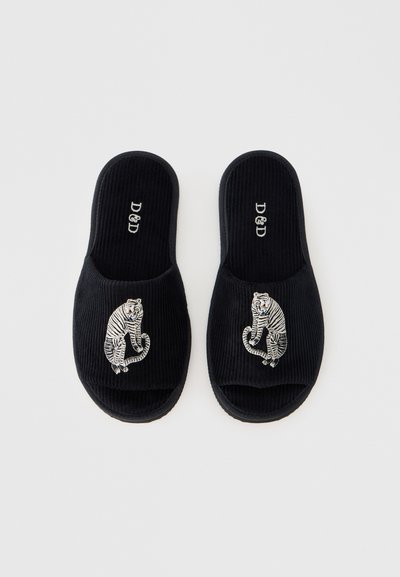 Μαύρες παντόφλες από κορδούρα με κεντητό σχέδιο τίγρης στο μπροστινό μέρος. Οι σόλες είναι επίπεδες και διαθέτουν απαλή υφή. Περιλαμβάνεται το λογότυπο της μάρκας.