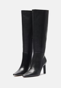 Schwarze kniehohe Lederstiefel mit spitzem Zehen und Stiletto-Absatz, ausgestattet mit einem Seitenreißverschluss und glatter Textur.
