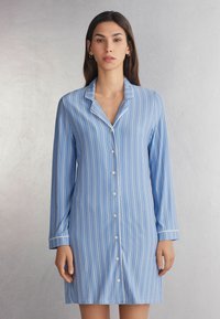 Niebieska w pasiaki, długosleeve nocna sukienka z kołnierzykiem typu notch, z przodem zapinanym na guziki oraz białymi lamówkami wzdłuż krawędzi mankietów i kołnierza.