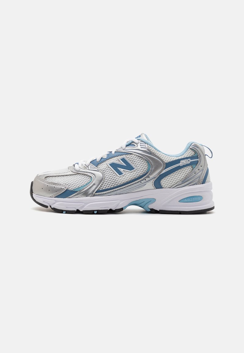 Scarpa da ginnastica argento e blu chiaro con parte superiore in rete, design della suola curvo, colletto imbottito e logo "N" sul lato. Presenta accenti di cuciture a vista.