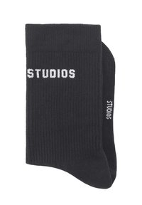 Schwarze, gerippte Socken mit weißem "STUDIOS"-Schriftzug. Bieten eine enge Passform und eine weiche Textur, ideal für den Alltag.