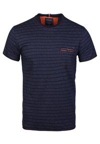 T-shirt à manches courtes bleu marine avec un motif texturé, col rond et une poche poitrine bordée de couture rouge. Tissu doux.