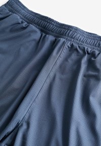 Granatowe spodenki sportowe z elastycznym pasem, wykonane z teksturowanej, przewiewnej tkaniny oraz szwami płaskimi dla dodatkowego komfortu.