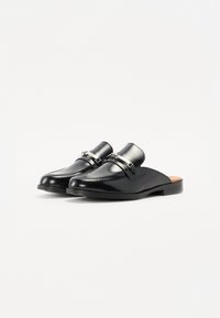 Mule in pelle nera con punta arrotondata, dettagli decorativi in argento e cuciture sulla tomaia. Suola piatta con soletta marrone chiaro.