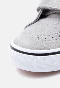 Κοντινή λήψη της μύτης ενός γκρι σουέντ πάνινα παπούτσια με λευκή καουτσούκ σόλα που διαθέτει υφή για καλύτερη πρόσφυση και μαύρη ρίγα.