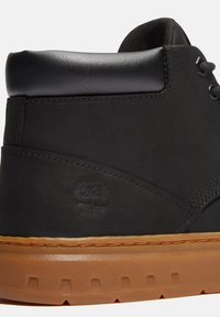 Svart läderankelboot med en slät yta, gummisula och pr präglad logotyp. Har förstärkta sömmar och en vadderad krage.