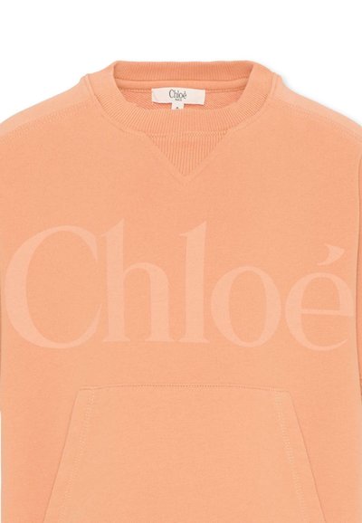 Sweat-shirt couleur pêche avec col rond côtelé, grande poche avant et logo discret "Chloé" sur la poitrine.