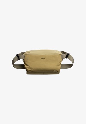 Sac bandoulière en nylon beige avec sangle réglable, fermeture éclair et détails de couture subtils. Logo présent sur le devant.