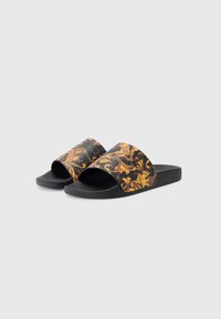 Chinelos de slide pretos com uma sola texturizada, apresentando padrões ornamentais em preto e dourado nas tiras largas. Inclui detalhes subtis de marca.