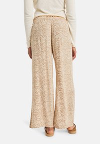 Pantaloni beige a gamba larga con motivo floreale, realizzati in tessuto leggero, dotati di una vita elastica e di una texture liscia.