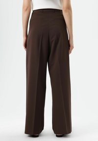 Pantalon large marron avec une texture lisse, doté d'une taille haute, de deux poches à l'arrière et d'une coupe droite.