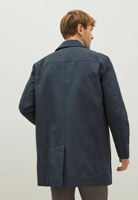 Marineblå, mellemlang frakke med back vent og spidse krave. Fremstillet af glat stof, med et rent, minimalistisk design.