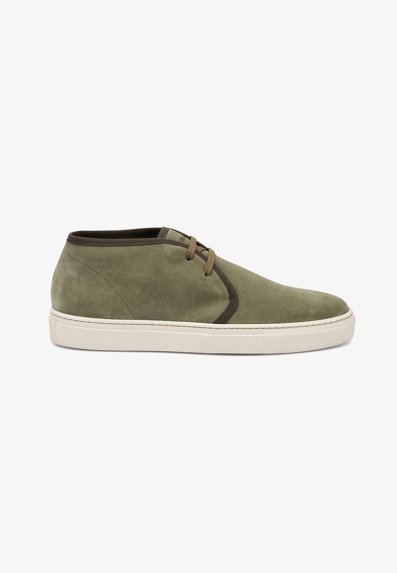 Scarpa con tomaia in suede verde e suola in gomma bianca, dotata di lacci marroni. Il design presenta cuciture minime e punta arrotondata.
