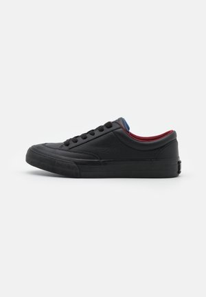 Czarny niski sneaker z sznurowaniem z przodu, teksturowaną podeszwą i czerwonym, wewnętrznym wyściółką, prezentowany na białym tle.