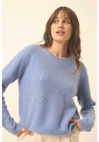 Hellblau gestrickter Pullover mit Rundhalsausschnitt, gerippten Bündchen und lockerer Passform. Weiche Textur mit zusätzlichen Details im Webmuster.