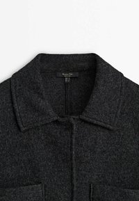Dunkelgrauer Wollmantel mit strukturiertem Kragen, vorderem Knopfverschluss und zwei aufgesetzten Taschen. Weiche Textur und taillierte Gestaltung.