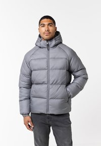 Chaqueta gris acolchada con capucha, que presenta secciones acolchadas y un cierre frontal. Puños elásticos y bolsillos laterales para mayor practicidad.