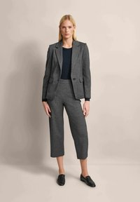 Gray tailored blazer with matching cropped trousers, textured fabric, black top underneath, and black loafers. Minimalist design, fitted shape.