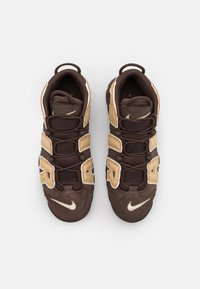 Bruna sportskor med guldaccenter, som har en ovandel i mesh och mocka, gummisula och tre kardborreband för en säker passform.