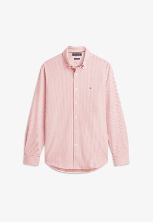 Chemise à manches longues avec boutons, rayée verticalement en rouge et blanc, avec un petit logo sur la poitrine gauche, étalée à plat sur un fond blanc.