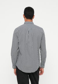 Černobílá kostkovaná košile, dlouhý rukáv s knoflíkovými manžetami, s klasickým límcem a rovný střih.