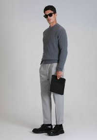 Grau gestrickter Pullover, hellgraue maßgeschneiderte Hose, schwarze Schuhe und schwarze Aktenmappe. Lässiges Design mit gerippter Textur und schmaler Passform.