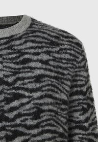 Tröja av mjukt, fluffigt tyg i grå och svart tigerrandig mönster. Har en ribbad halsringning och en strukturerad, lätt finish.