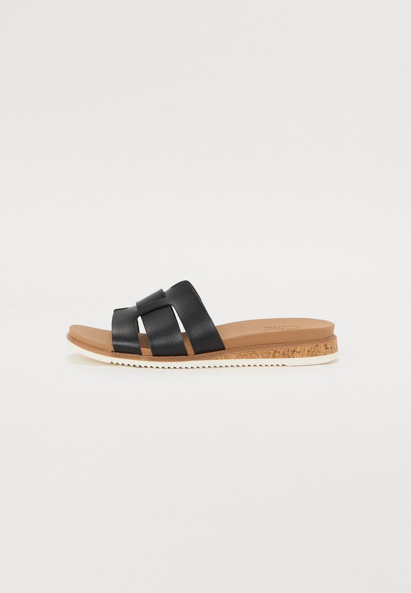 Svart slidesandal med tre brede stropper laget av teksturert materiale. Lys brun fotbed og en korkteksturert såle med hvite detaljer.