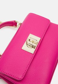 Růžová kožená kabelka s texturou, zlatým zapínáním a odnímatelným popruhem. Má obdélníkový tvar a prošité okraje.