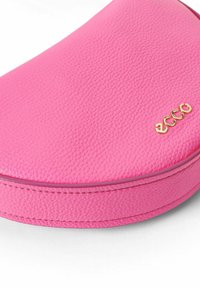 Borsa in pelle rosa con superficie testurizzata, caratterizzata da un design curvo e logo "ecco" dorato. Cuciture lisce lungo il bordo.