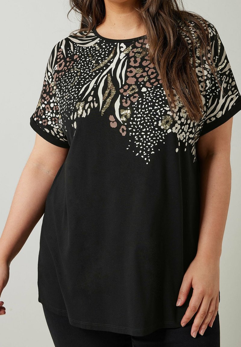 Haut noir à manches courtes avec motifs animaux mélangés en marron, blanc et or sur le haut de la poitrine et les épaules.
