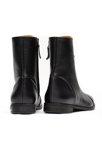Black leather ankle boots with a smooth finish, featuring a side zipper and minimalistic design. Flat, sturdy sole with subtle accents.